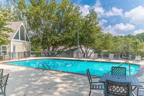 a swimming pool with a table and chairs and a house in the background